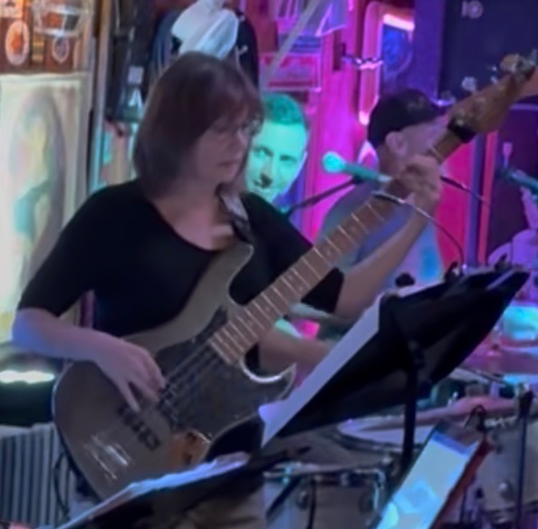 Charise Rogosky playing bass on stage under pink lights